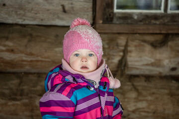 A little girl enjoys the sunny and cold winter wonderland of the north. The old log walls crackle from the frost.