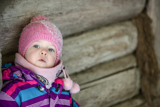 A little girl enjoys the sunny and cold winter wonderland of the north. The old log walls crackle from the frost.