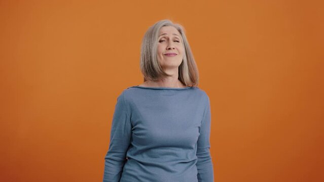 Elderly woman frowns and shows thumbs-down disapprovingly