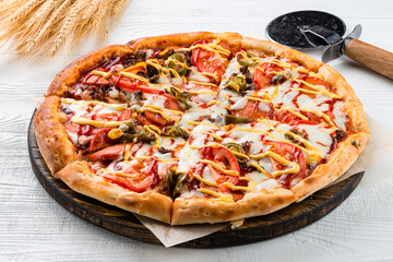 Italian cuisine pizza with sausages, jalapeno pepper, mozzarella, tomatoes and sauce.