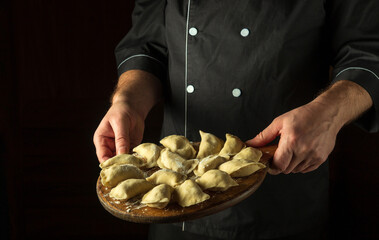 Cooking dumplings in the kitchen of the restaurant by the hands of the cook. Delicious breakfast or lunch idea with place for recipe or menu.
