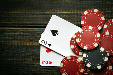 Playing cards with a winning combination of one pair and chips on a black vintage table in a poker club. Copy space for advertising.