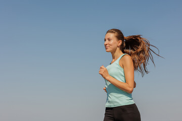 portrait of sporty woman jogging in morning on ocean. young confident woman runs to marathon and takes care of physical and mental condition. healthy lifestyle. fitness and yoga