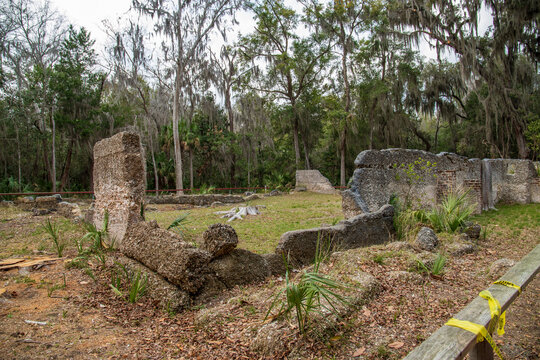 The crumbled walls of the Taby Ruins surrounded lush green trees, plants and grass with blue sky and clouds at Wormsloe Historic Site in Savannah Georgia USA