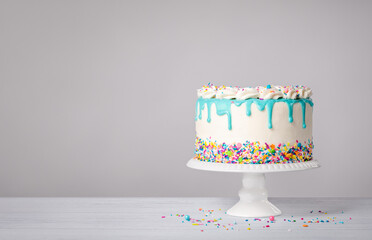 Birthday Cake with a blue ganache drip and colorful sprinkles on a white background - 580157354