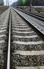 Railway rails on reinforced concrete sleepers on stone ballast go into perspective