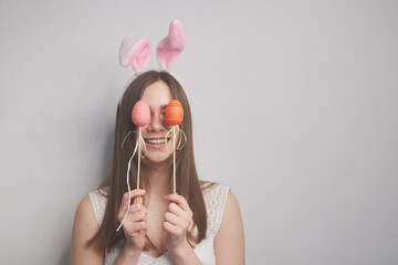 a girl with rabbit ears in her hands holds easter eggs, on a white background, the concept of easter