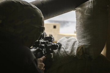 Ein Soldat zielt mit seinem Gewehr aus seiner Stellung auf ein Gebäude bei einer Übung. 