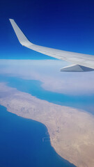 View from the window of plane on blue sky and earth with landscape of desert, sea and canals in Emirates. High quality photo