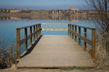 Puente flotante sobre un lago que parece un espejo, donde se refleja todo el paisaje.