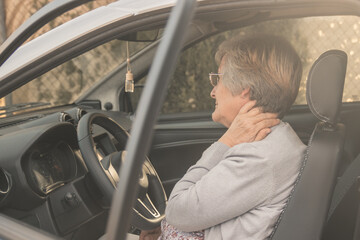 Senior woman having neck pain while driving a car. Old woman feeling bad about an injury