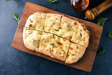 Crispy pinsa with rosemary in wooden board.