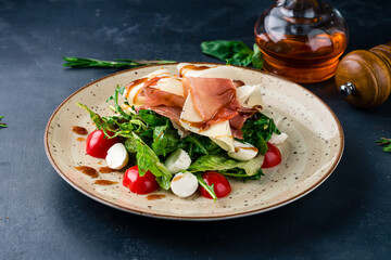 Fresh salad with cherry tomatoes, mozzarella cheese, bacon, parmesan, lettuce and arugula.