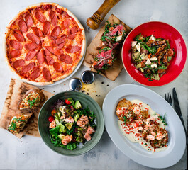 Set pizza pepperoni, salads with chicken and salmon, potato pancakes with salmon and red caviar and bruschetta.