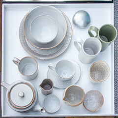 A wide variety of white plates bowls and mugs lined up. Top view. Square frame