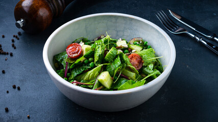 Fresh green salad with cucumbers, lettuce, cherry tomatoes, arugula, beets, green peas, red onion and nuts.