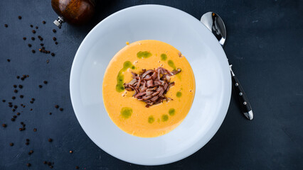 Pumpkin cream soup with fried bacon and oil.