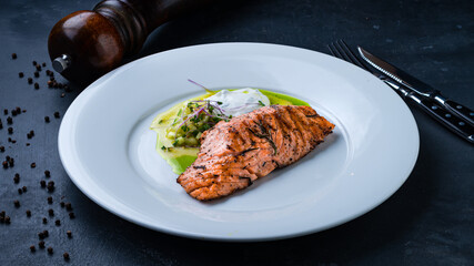 Grilled salmon fillet with salad of cucumbers, microgreens and sauce.