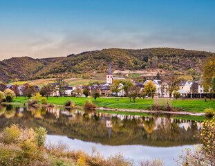 Fototapeta na wymiar Long exposure shot of Bruttig-Fankel village on moselle river and vineyards during autumna in Cochem-Zell, Germany