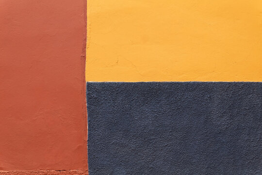 Colorful Mexican exterior wall painted in shades trim colors and off CENTERED, distressed textures