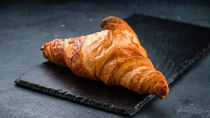 French breakfast fresh croissant on black background.