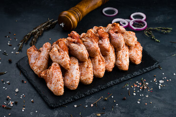 Marinated barbecue chicken legs on a dark background.