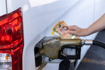 Costa Rica, gas station, woman holding a handful of money by the car, Concept, Rising fuel prices,...