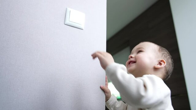 Sweet smiling little toddler and his daddy playing with light. Father and son take turns in switching the light on and off. Low angle view.
