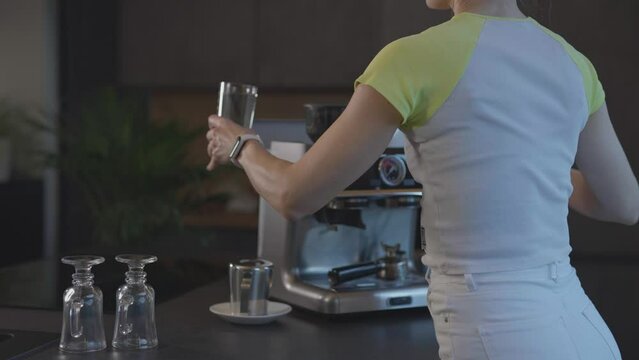 Caucasian female is filling water tank of espresso machine with fresh water