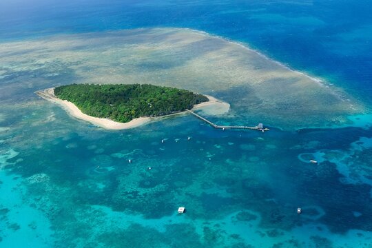 An aerial view of the coral reefs and clear turquoise waters surrounding Green Island, a small tropical isle in the outer Great Barrier Reef &mdash; Coral Sea, Cairns; Far North Queensland, Australia