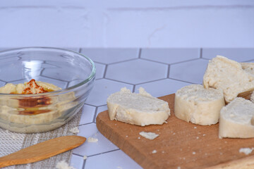 Close-up of a glass container with homemade chickpea hummus, bread and spreader.