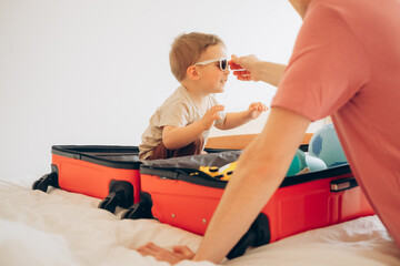 Father and son on bed packing suitcase. travel concept