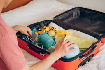 man packing suitcase on bed, closeup