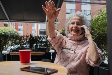 Mujer mayor en cafeteria  sonríe y llama al mesero