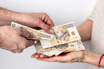 Dłonie mężczyzny i kobiety wymieniających się pieniędzmi. Banknoty na białym tle. Liczenie pieniędzy. - obrazy, fototapety, plakaty