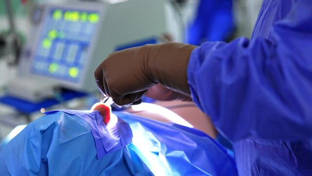 Surgeon’s hands in sterile gloves shoving instruments into nose of a patient. Assistant passing tools to a doctor. Close up. Blurred backdrop.
