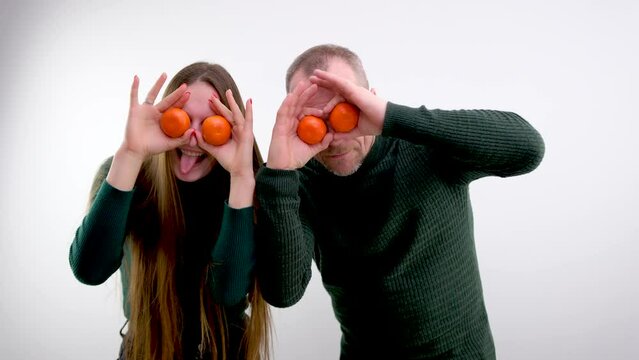 man and girl fooling around balding man and long-haired daughter joking playing troll each other tangerines holding tangerines near eyes for sale fresh fruits in city buy exotic fruits at low prices