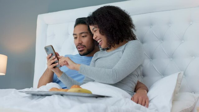 Smartphone, laugh and couple in bed to relax and watch a video on social media or the internet. Happy, technology and young man and woman looking at funny picture or meme on cellphone in the bedroom.