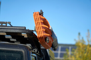 Close-up of Orange Recovery Tracks, boards, ladders mounted on the side of a roof rack on a 4x4 off-road vehicle