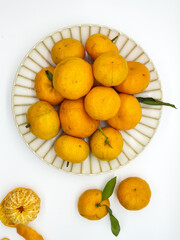 Orange fruit with green leaves on the white background. Home gardening. Mandarine oranges. Tangerine oranges. Orange color. Fresh orange juice.