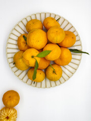 Orange fruit with green leaves on the white background. Home gardening. Mandarine oranges. Tangerine oranges. Orange color. Fresh orange juice.