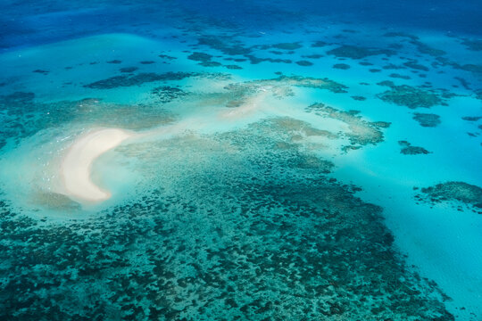 An aerial view of Michaelmas Cay in the Great Barrier Reef: tropical white sand bar, coral reefs, clear turquoise waters — Coral Sea, Cairns; Far North Queensland, Australia