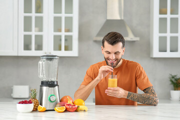 Fototapeta na wymiar Handsome man with delicious smoothie at white marble table in kitchen
