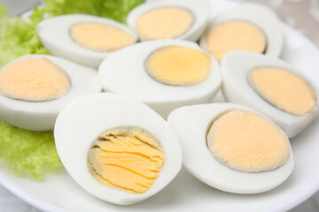 Fresh hard boiled eggs and lettuce on plate, closeup