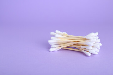 Wooden cotton buds on violet background. Space for text