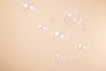 Many beautiful soap bubbles on beige background