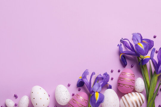 Flat lay composition with festively decorated Easter eggs and iris flowers on violet background. Space for text - Powered by Adobe