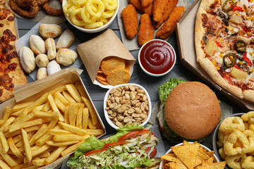 French fries, chips other fast food on gray wooden table, flat lay