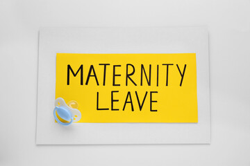 Note with words Maternity Leave and baby pacifier on white background, top view