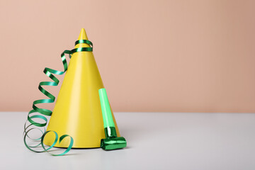 Colorful party hat, streamer and blower on white table, space for text. Birthday celebration